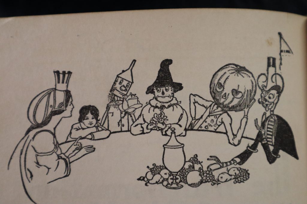 Tip, Glinda, and the characters from Oz sit around a table